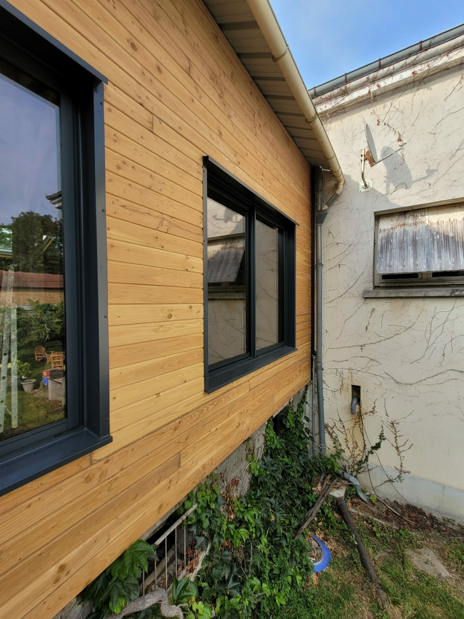 Façade bois moderne dkz contrastant avec mur ancien végétalisé, rénovation extérieure maison dans les Hautes-Pyrénées