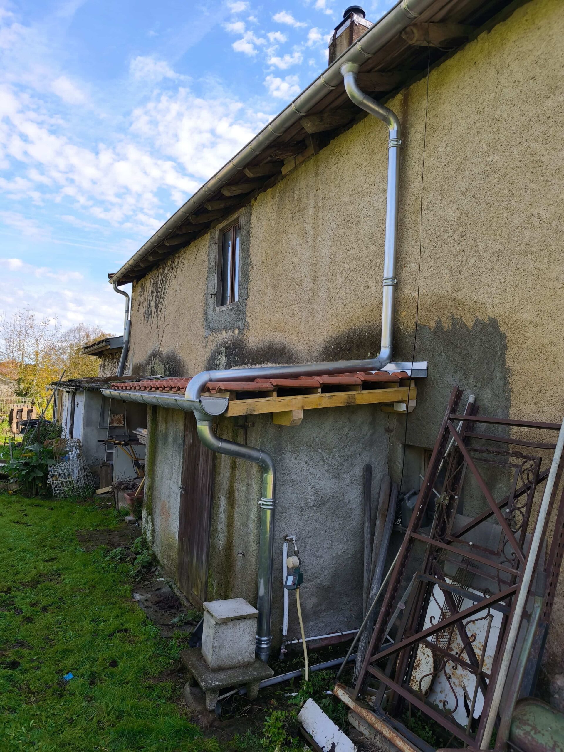 Gouttières zinc rénovées sur maison ancienne par dkz dans les hautes-pyrénées, façade beige et jardin verdoyant