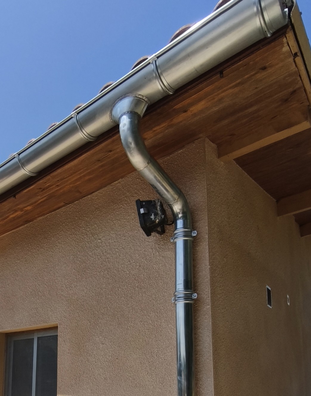 Gouttière zinc et nid d’oiseau en façade de maison beige, toiture tuile dkz hautes-pyrénées